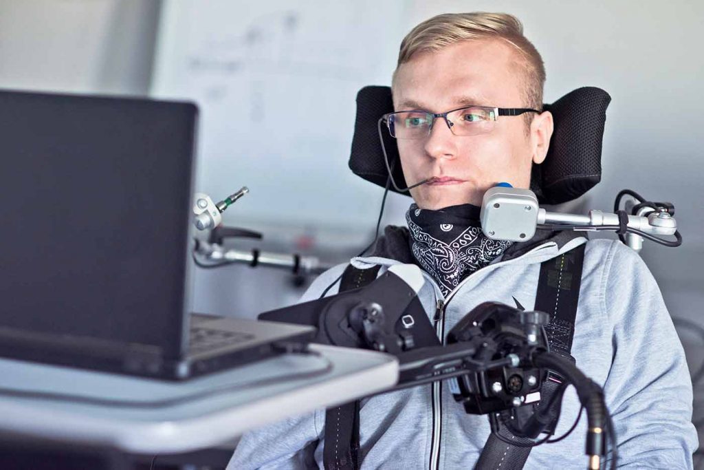 Persona con discapacidad física haciendo uso de un portátil con accesibilidad informática.