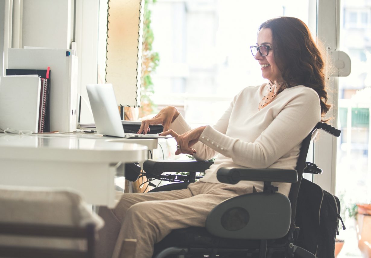 Mujer con discapacidad es feliz trabajando en un portátil gracias a la accesibilidad informática