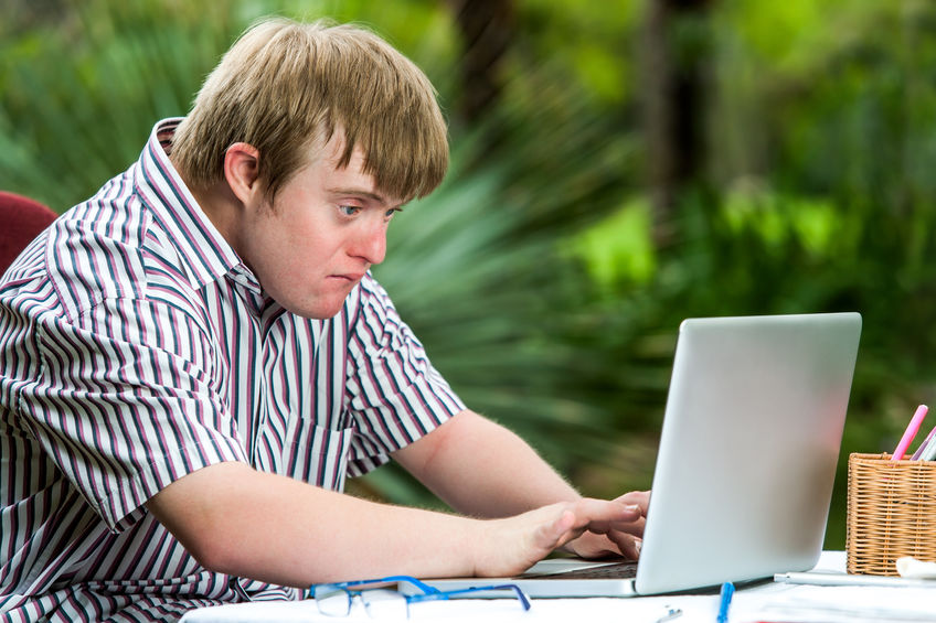 young man with down syndrome uses laptop computer
