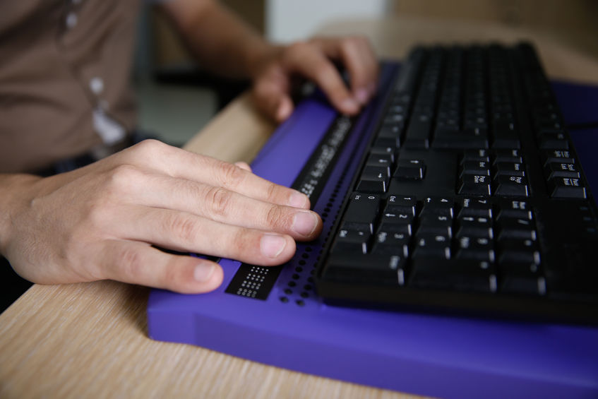 unas manos utilizan un teclado de ordenador especial para personas con discapacidad visual