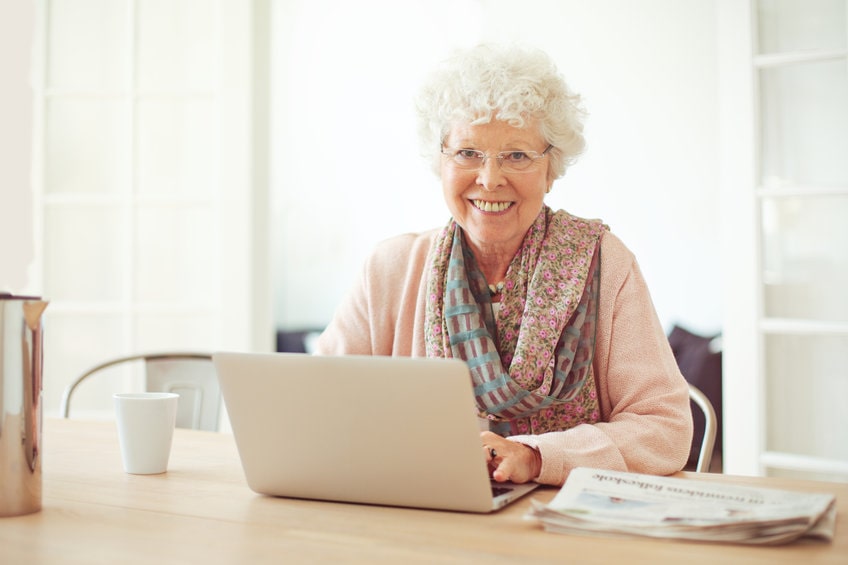 Cheerful older woman using laptop as home recreation