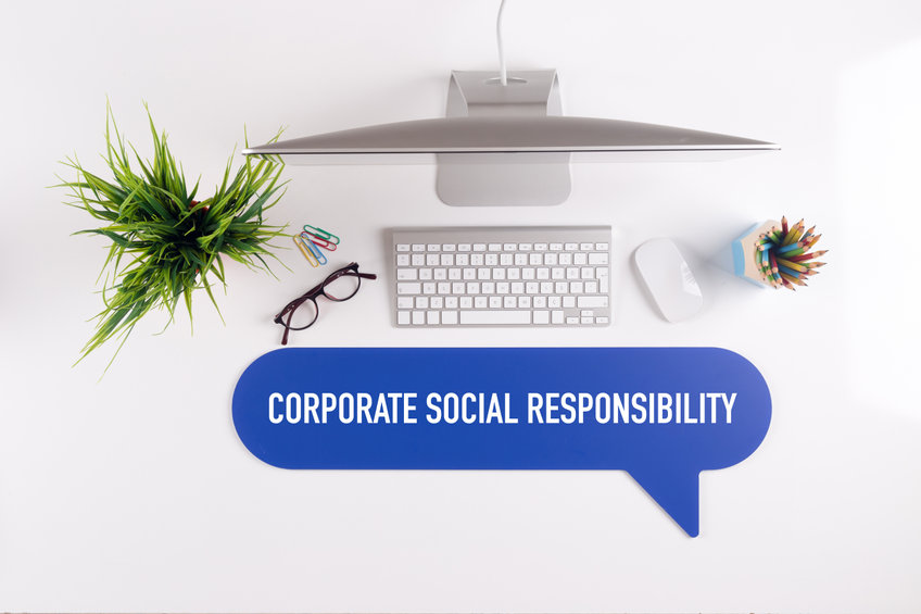 aerial view of an office desk with a computer and a sign with the text corporate social responsibility.