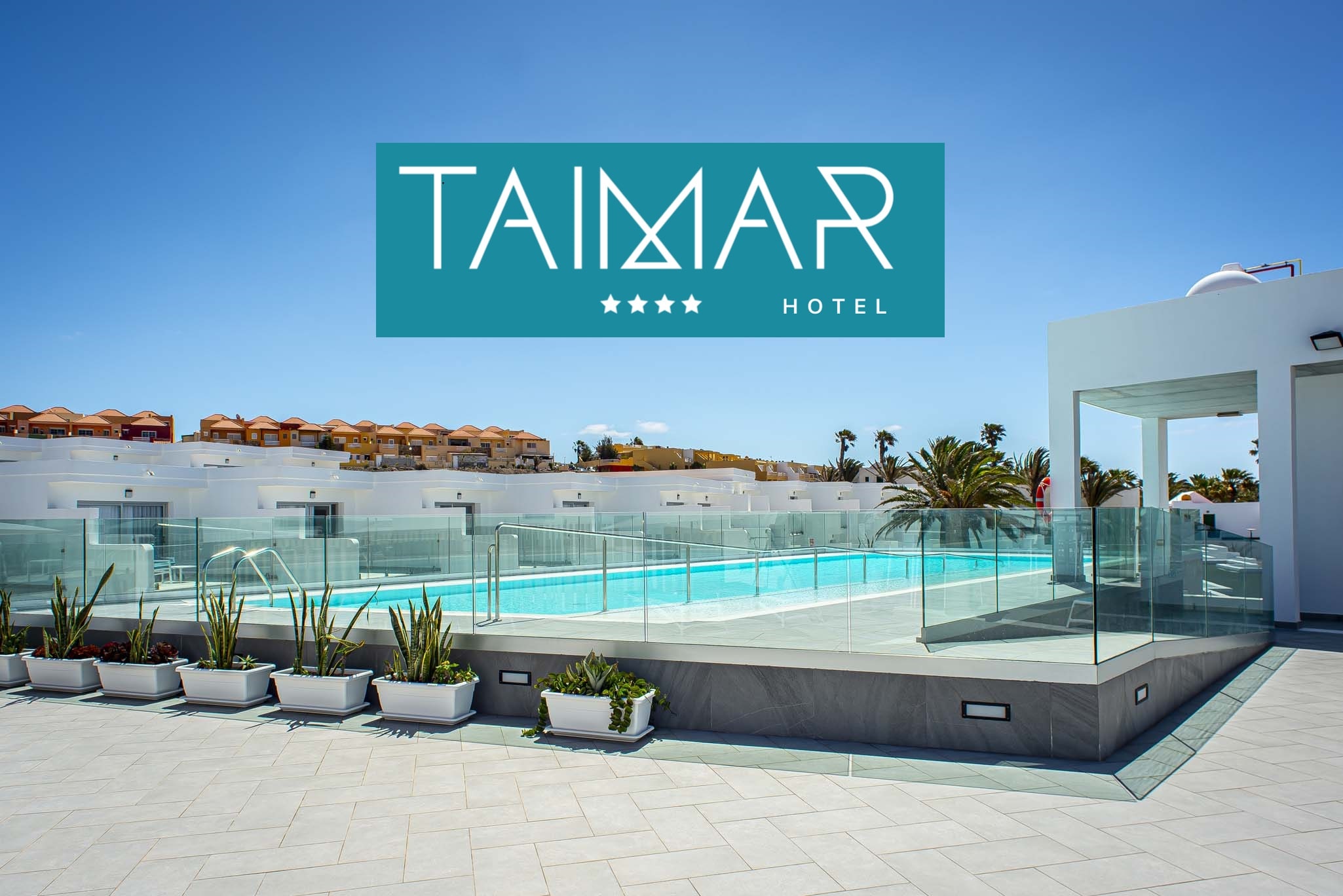 vista panorâmica do complexo de edifícios que formam o Hotel Taimar e uma piscina ao ar livre com rampa para pessoas deficientes.