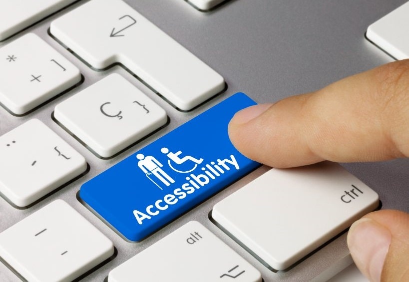 Dedo presionando una tecla azul del teclado que tiene la palabra "accesibilidad" escrito en ella.