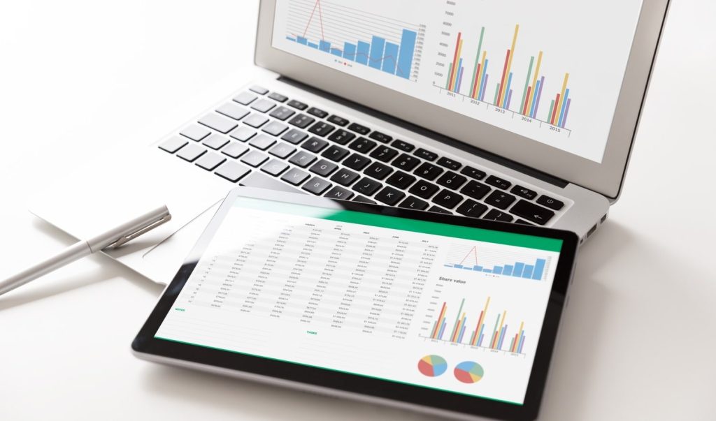Ordenador portátil y una tablet sobre una mesa, ambos mostrando pantallas con gráficos analíticos