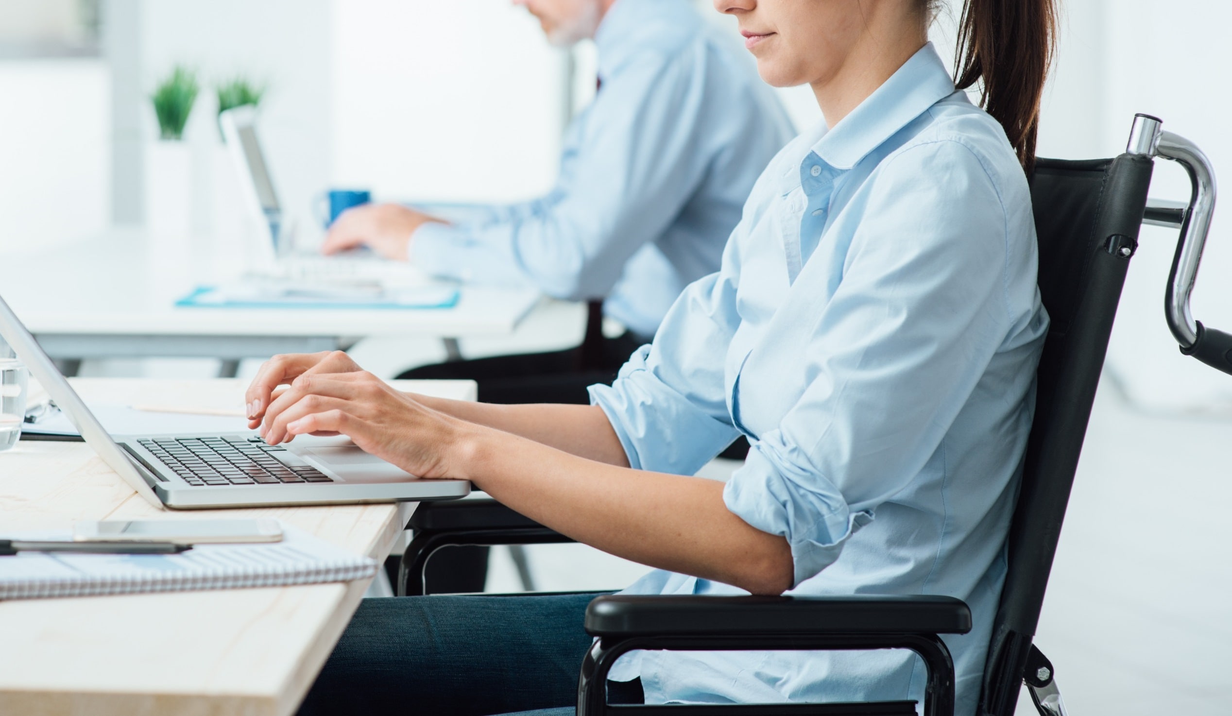 Mujer joven con discapacidad trabajando con un ordenador portátil en un puesto de oficina