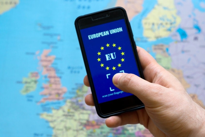 Main tenant un téléphone portable avec le symbole de l'Europe affiché à l'écran, en référence à la directive 2019/882 ou Acte européen sur l'accessibilité.