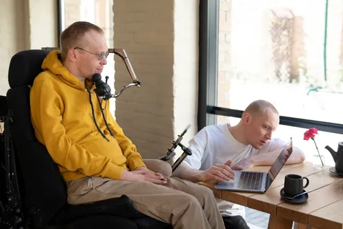 Un hombre prepara un entorno digital para otro hombre con discapacidad.